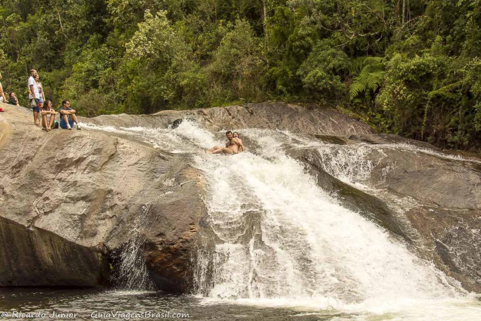Imagem de um casal descendo na Cachoeira do Escorrega em Visconde de Mauá.